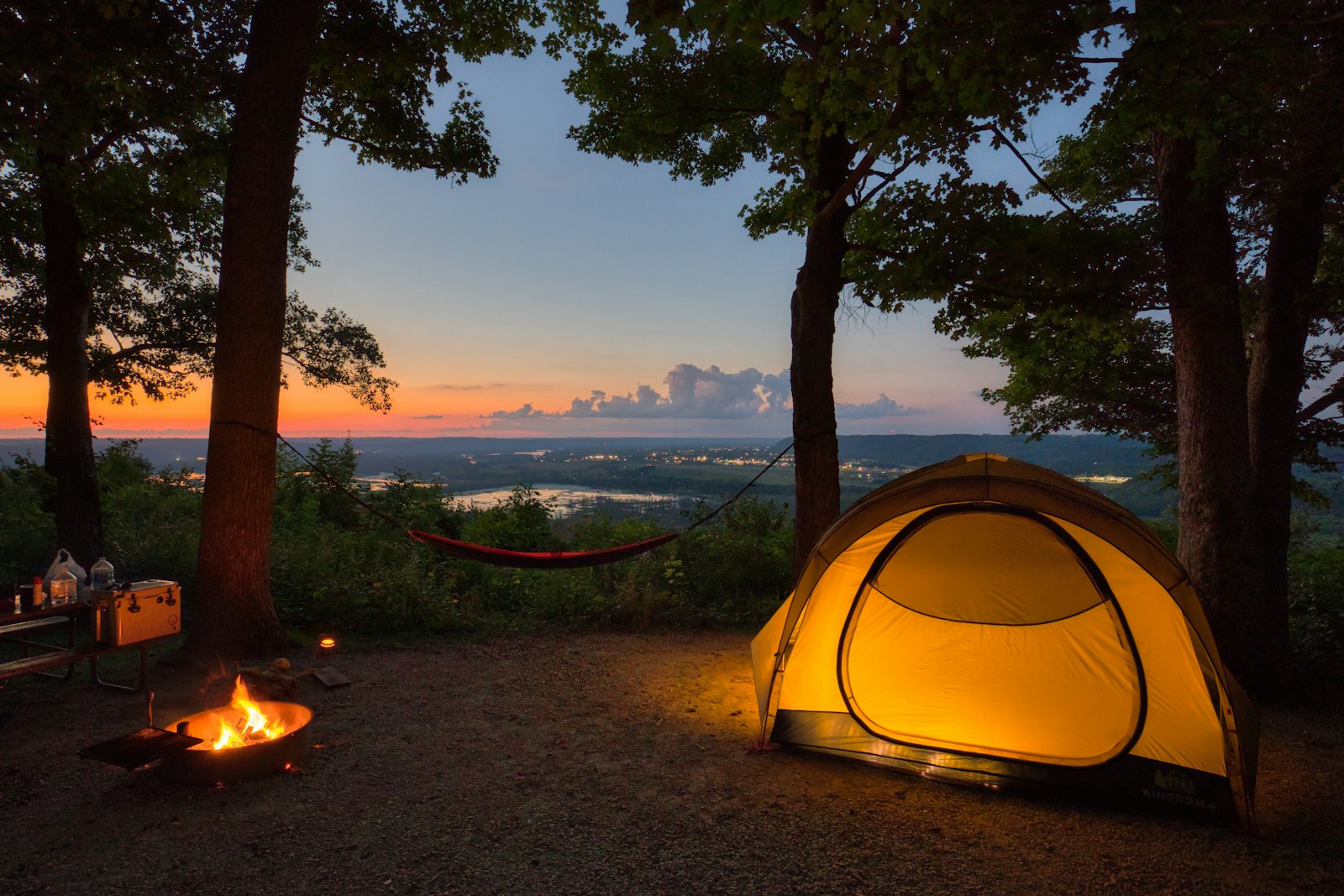 Tent and small campfire in the woods at sunset